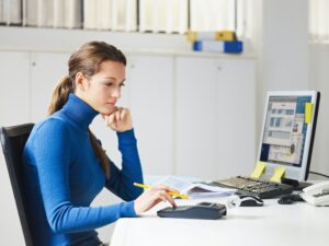 Female Young Secretary Using Calculator In Office