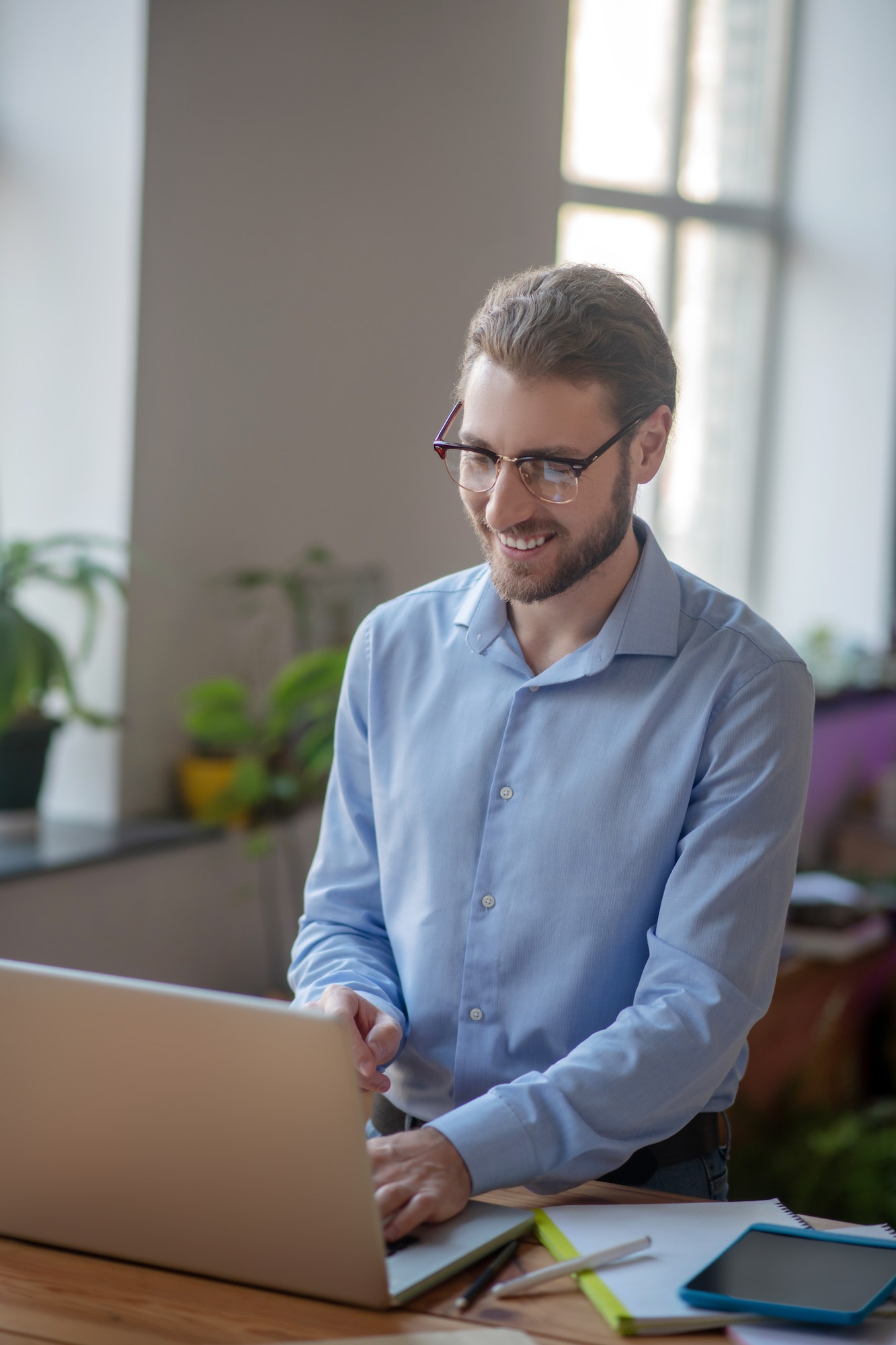 Young joyful man working on a laptop in an office.